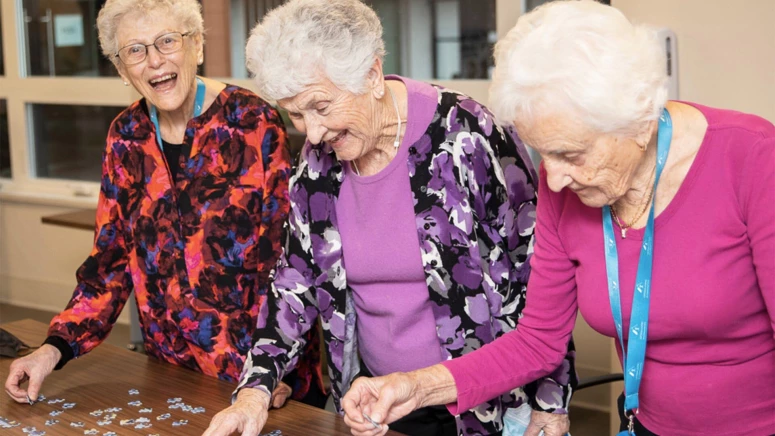 Three senior women completing a puzzle together