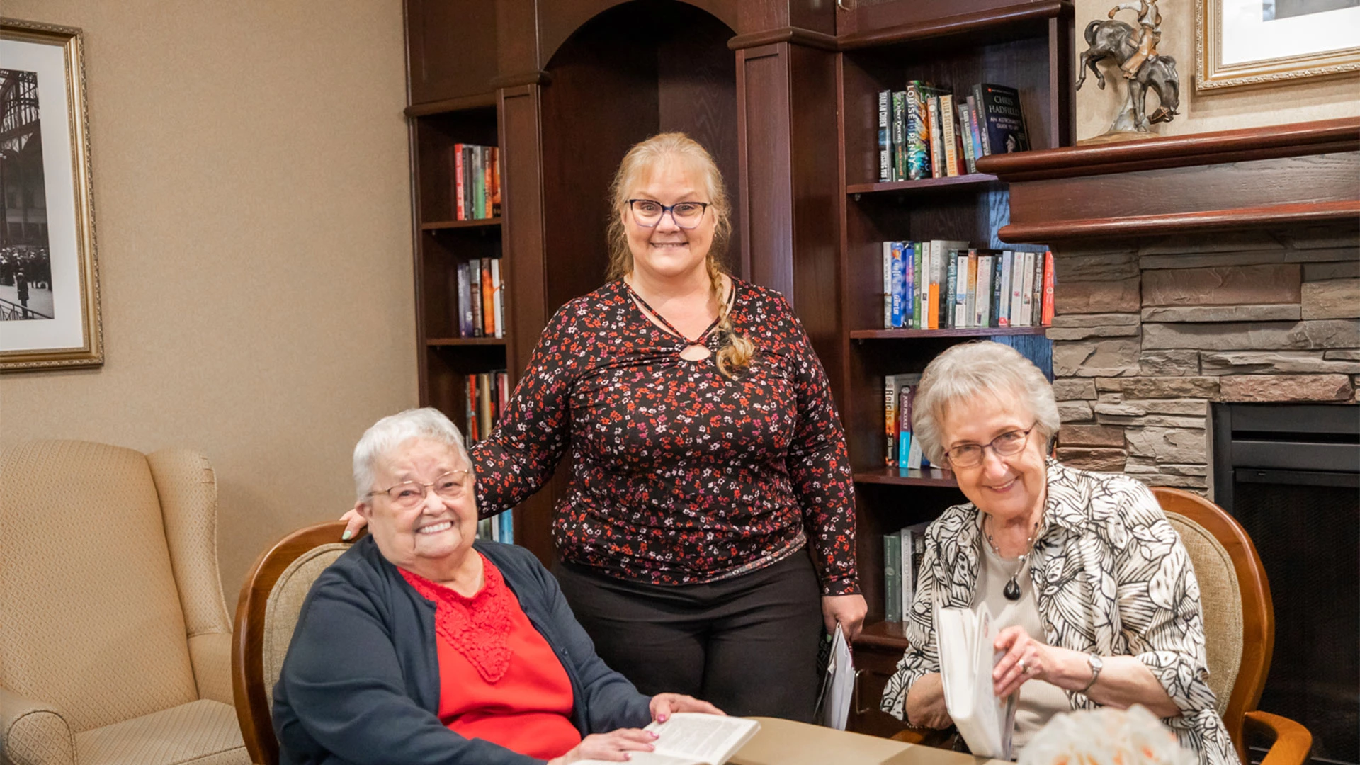 Seniors smiling with a staff member in the library